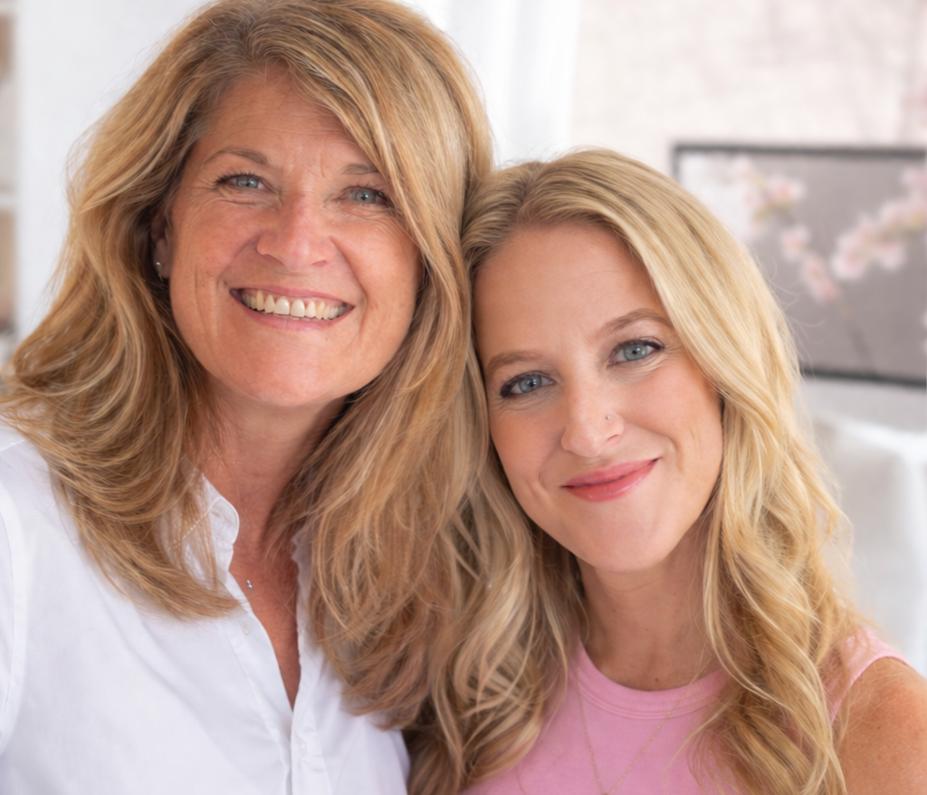 Two women with blonde hair posing together indoors.